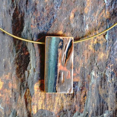 Bronzeanhänger auf Stein Ein rechteckiger Anhänger mit Halsband, beide goldglänzend