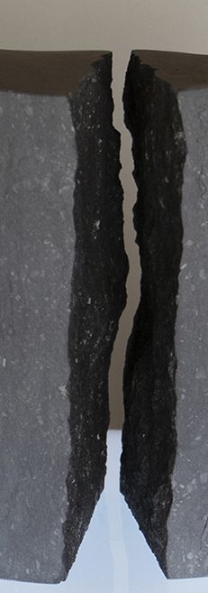 Grauer Stein Zwei geschliffene, fast schwarze Steine mit gegenüberliegenden Bruchkanten